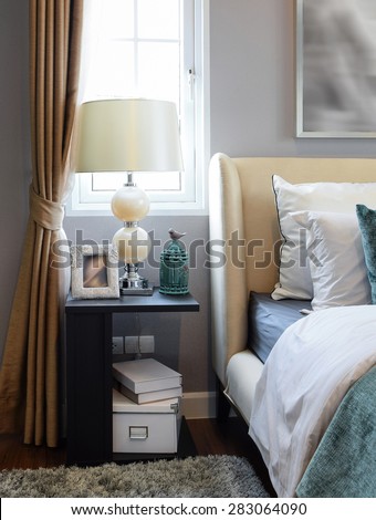 bedroom interior design with white and green pillows on white bed and decorative table lamp.