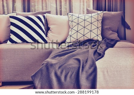 vintage style photo of L-shape sofa with varies pattern pillows in living corner