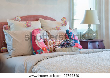 colorful pillows and bedside table lamp in modern kid bedroom interior