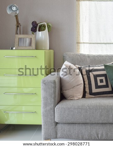 Cozy sofa with geometric pattern pillows and green sideboard in living corner