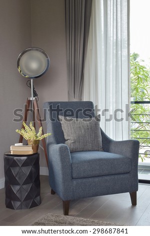 Light blue armchair with gray pillow and retro lamp in the living room