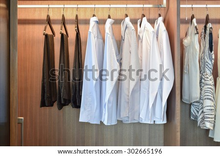row of white shirts hanging in wooden wardrobe