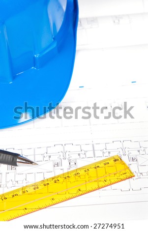 Construction plans with hard hat and drawing tools. Shallow depth of field