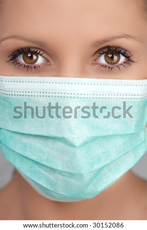 Half body portrait of young woman wearing protective medical face mask, studio background.