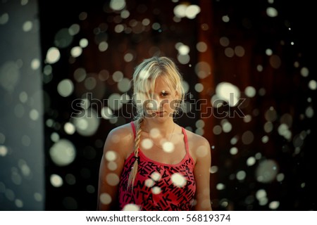 Half body portrait of young woman in summery dress with snow falling in foreground.