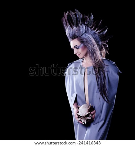 dark fashion shot of a woman holding a evil skull, crazy hairstyle with feathers