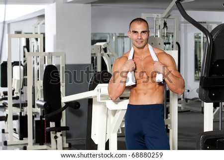 young caucasian bodybuilder in the gym smiling, with a towel around his neck