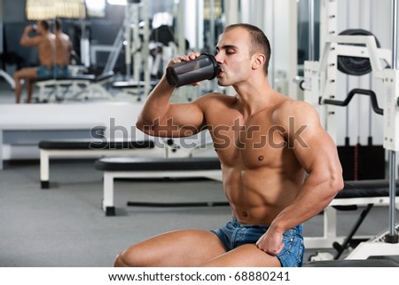 young caucasian bodybuilder in the gym, drinking a protein shake