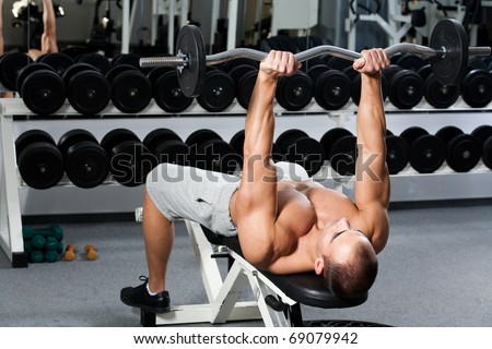 young bodybuilder training in the gym - triceps - lying E-Z curl bar press