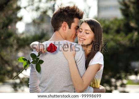 romantic moment: young man giving a rose to his girlfriend