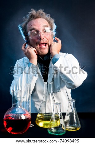 Scientist in white lab coat, with ear plugs and fingers in his ears, waits for a possible explosion