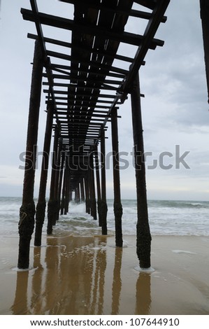 Wooden Bridge on the beach with waves and reflection - vertical image