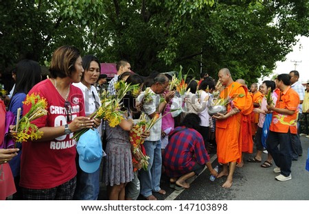SARABURI, THAILAND-JULY 23: Crowd of unidentified people offer flowers to unidentified monks in Buddhist ceremony at Phrabuddhabat temple on July 23, 2013 in Saraburi, Thailand.