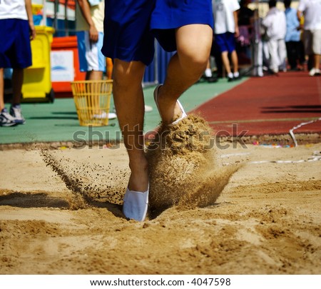 Runner jumping into the sands. HighSchool Sport Event.
