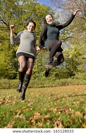 laughing sisters jumping in autumn park