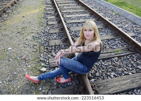 pretty young woman sitting on rail track