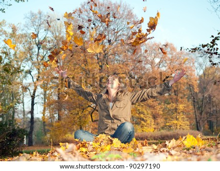 young woman playing with autumn leaves