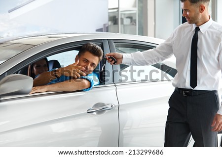 Car Salesman Handing over new Car Key to Customer at Showroom
