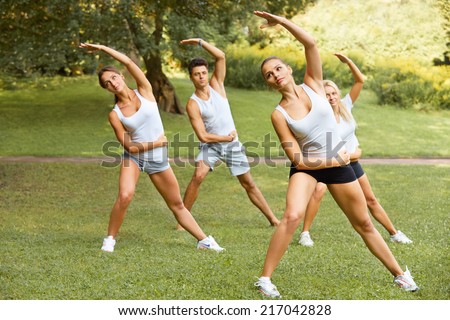 Fitness class. Portrait of smiling people doing fitness exercise at summer park