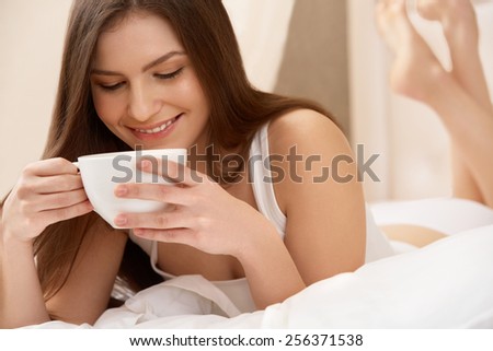 Woman Holds Cup of Tea Lying on the Bed.