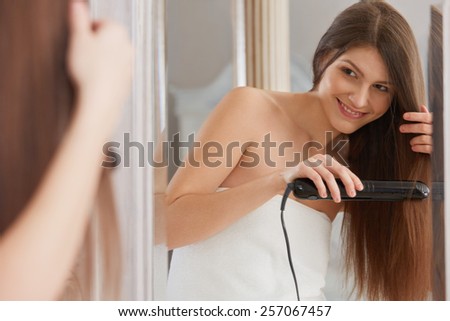 Woman straightening hair with straightener