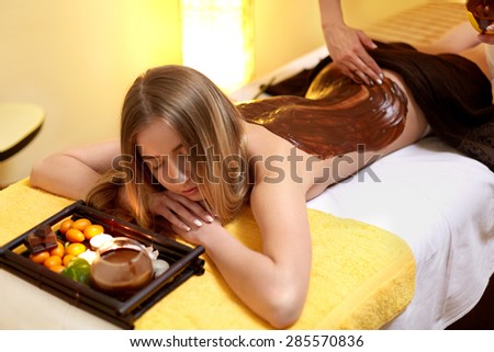 Spa Woman. Young Woman Gets Chocolate Body Mask at Beauty Salon