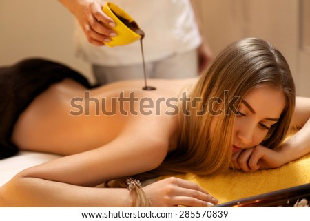 Spa Woman. Young Woman Gets Chocolate Body Mask at Beauty Salon