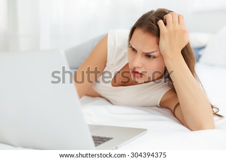 Depressed Pregnant Woman Works at Laptop Computer While Lying on a Bed