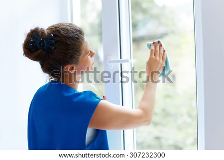 Young Woman cleaning window glass. Cleaning Company Worker