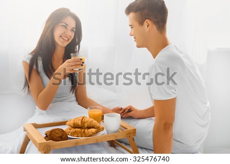 Happy young smiling couple having romantic breakfast in bed in the morning. Love and care. Relationship concept. White background.