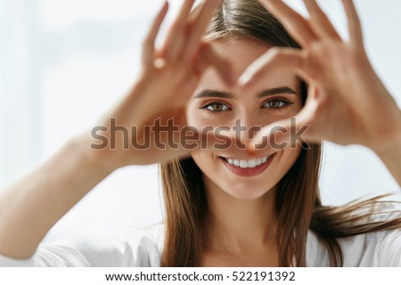 Healthy Eyes And Vision. Portrait Of Beautiful Happy Woman Holding Heart Shaped Hands Near Eyes. Closeup Of Smiling Girl With Healthy Skin Showing Love Sign. Eyecare. High Resolution Image Stockfoto © 