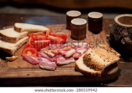 Bacon, tomato, bread and moonshine on the table