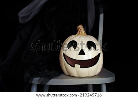 View of Halloween Pumpkins, a witch\'s hat and a cape on a chair against a dark background
