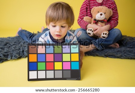 Child holding a custom white balance grey card for a photography session.
