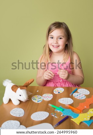 Happy smiling child doing Easter activities and crafts with bunny stickers, Easter Egg shapes, pencils and markers.