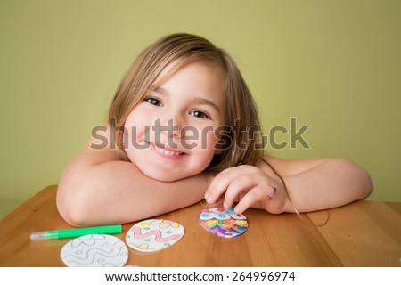 Child doing Easter activities and crafts with Easter Egg shapes, pencils and markers.