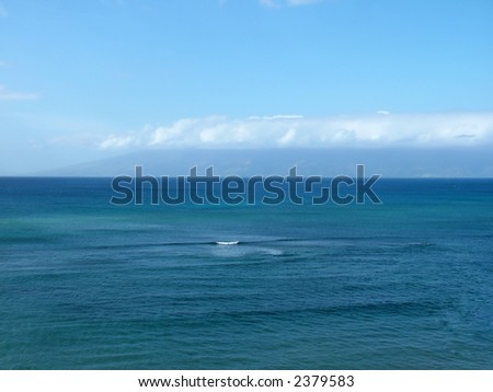 View of an ocean against blue sky with land and cloud in the background