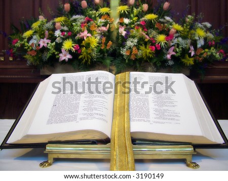 View of an open Bible on an altar, flowers in the background