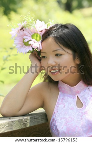 Beautiful Asian female with flowers in a summer time, park setting