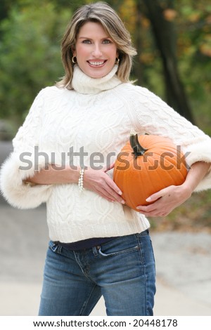 Seasonal, Pregnancy Theme: Gorgeous pregnant woman in a white sweater with a pumpkin, portrait. Suitable for a variety of seasonal, parenting, advertising themes