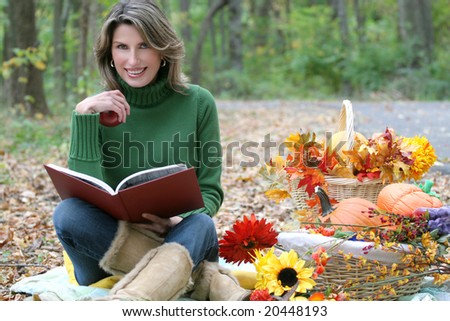 Reading a book in a park - attractive female having a leisurely day in a park, reading a book, in a fall setting with flowers and baskets. Suitable for a variety of seasonal, recreational themes