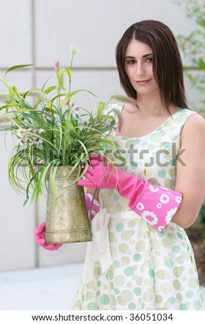 Attractive Caucasian woman gardening: pink gloves, plant in a pot