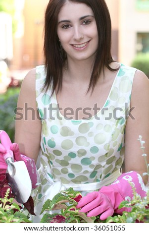 Attractive Caucasian woman gardening: pink gloves, plant in a pot