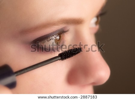 close-up of mascara brush about to be applied to eyelashes, selective focus on brush