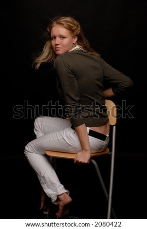 Portrait of a blond girl on a chair turned away