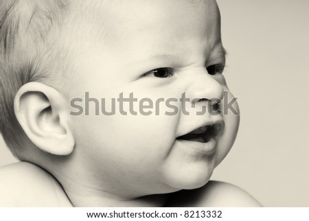 Black and White Close up portrait of little baby looking sideways to the left smiling