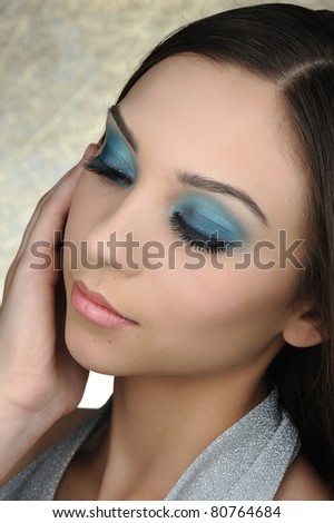Closeup of a glamorous young woman with closed eyes agaisnt golden background