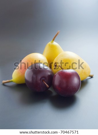 Plums and pears. Two fresh ripe  plums and three pears close-up arranged on gradient background