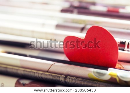 Heart in red cardboard between the folds of a magazine