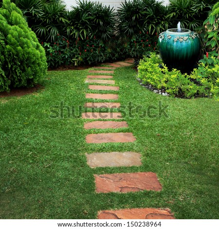 green jar fountain and stone walk way in garden